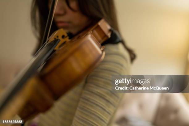 multiracial young woman prepares for violin performance - classical orchestral music stock pictures, royalty-free photos & images