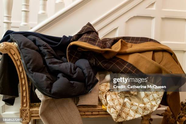 pile of coats on chair in foyer - abrigo fotografías e imágenes de stock