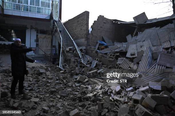 Resident looks at a collapsed building after an earthquake in Jishishan County, in northwest China's Gansu province on December 19, 2023. / China OUT