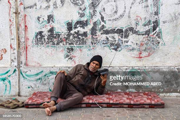 Palestinian old man listens to his radio in a refugee camp in Rafah in the southern Gaza Strip on December 17 amid continuing battles between Israel...