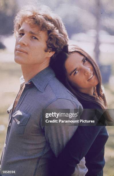 American actors Ryan O'Neal and Ali MacGraw stand back to back outdoors in a still from the film, 'Love Story,' directed by Arthur Hiller, 1970.
