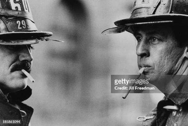 Two firefighters relax with a cigarette after a call-out in New York City, circa 1976.