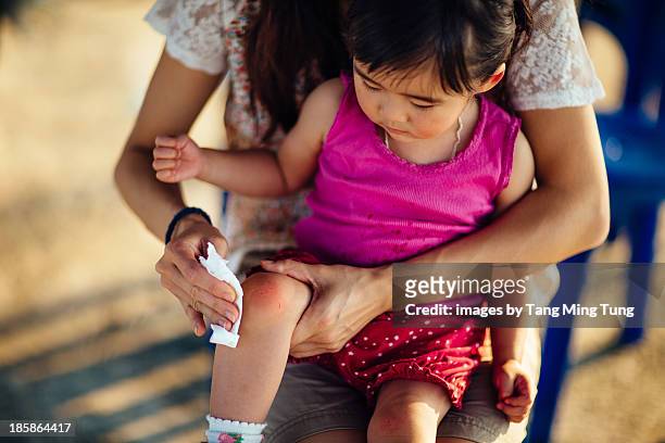 mom cleaning wound on knees for toddler girl - wounded photos et images de collection