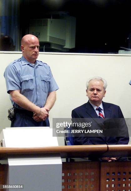 Former Yugoslav President Slobodan Milosevic is flanked by an officer in the courtroom of the UN War Crimes Tribunal in The Hague, 03 July 2001,...