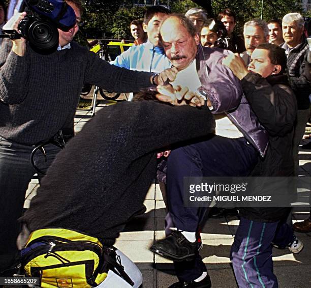 Supporter of former Argentine President Carlos Menem clashes with an unidentified member of the media 06 June outside a hotel in Buenos Aires where...
