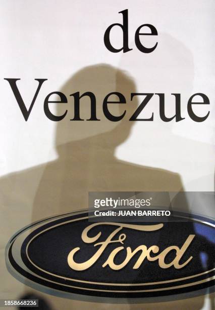 The shadow of Emmanuel Cassingena, president of FORD Venezuela, is projected on a poster with the logo of the company, while he answers questions...