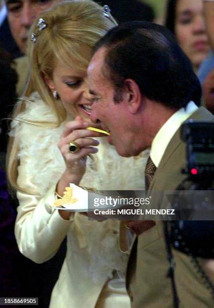 Former Argentine president Carlos Menem is fed wedding cake by his new bride Chilean former Miss Universe Cecilia Bolocco at the reception following...