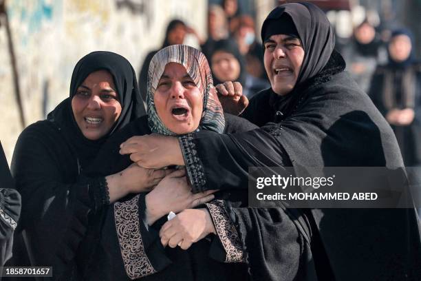 Graphic content / Women tend to the sister of Palestinian journalist Adel Zorob, who was killed overnight during Israeli bombardment, as she mourns...