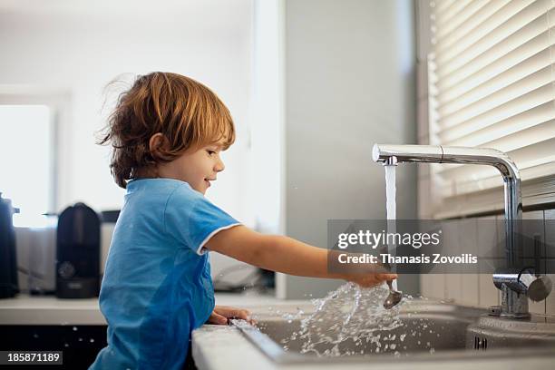 small boy playing with water - impianto domestico foto e immagini stock