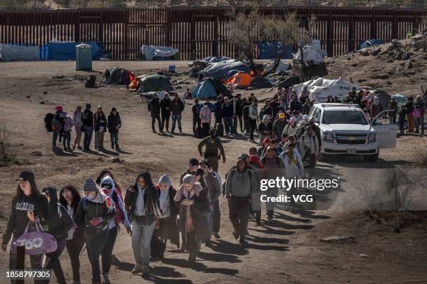 Asylum seeking migrants wait to be processed by the U.S. Border Patrol after crossing from Mexico at a makeshift camp next to the US border wall on...