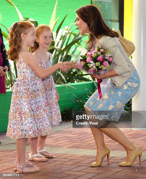 Princess Mary of Denmark receives flowers from identical twins Lillian and Charlotte Harding as the royal couple arrive for a visit to the Australian...