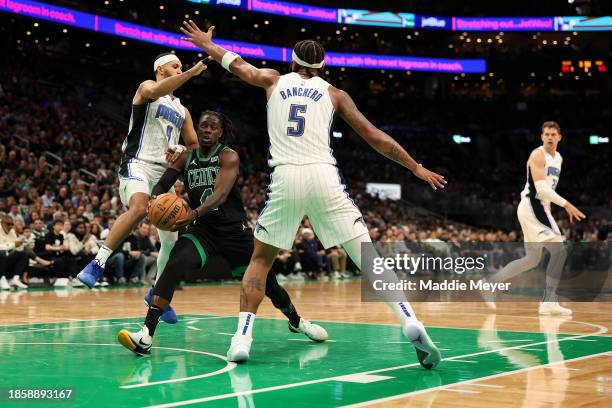 Jrue Holiday of the Boston Celtics looks for a pass between Paolo Banchero and Jalen Suggs during the second half at TD Garden on December 15, 2023...