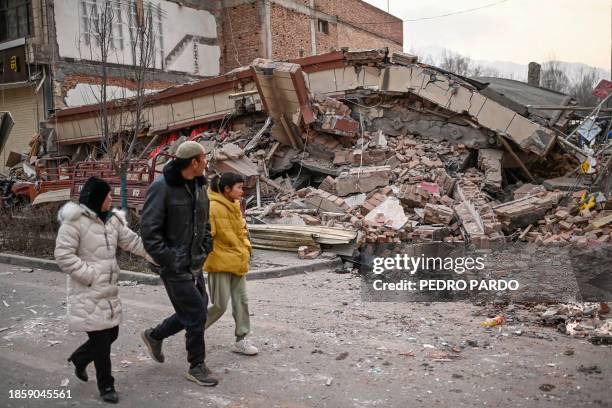 People walk past a collapsed building after an earthquake in Dahejia, Jishishan County in northwest China's Gansu province on December 19, 2023.