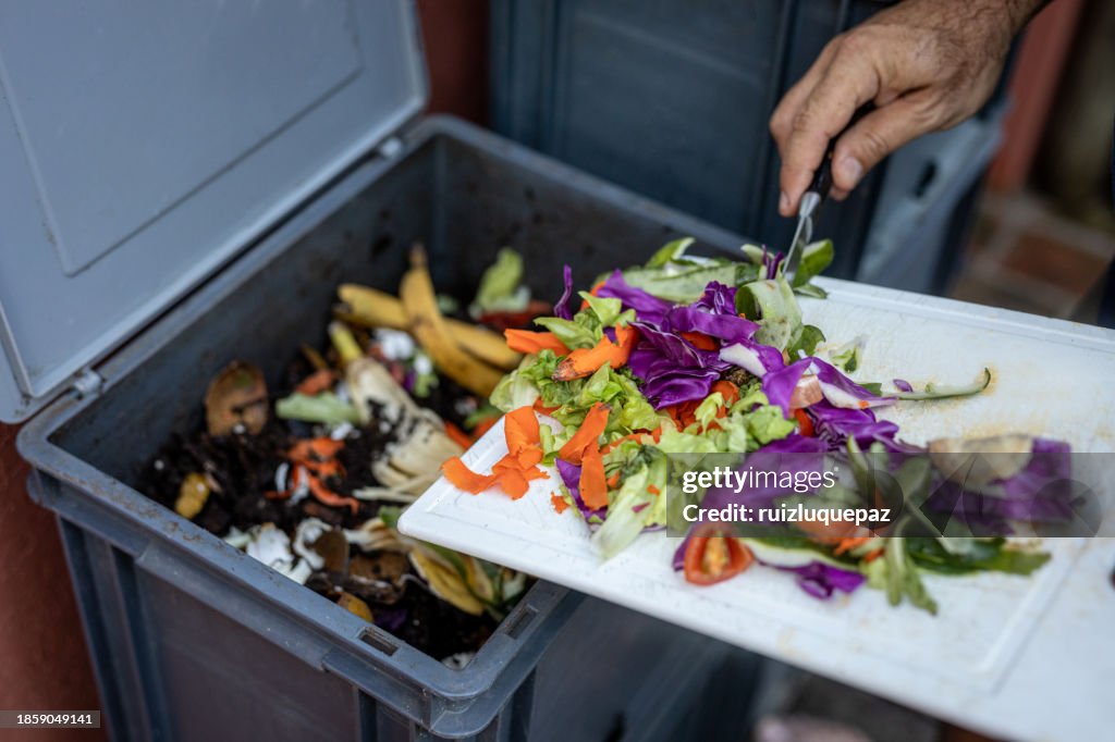 Man composting organic remains in home composter