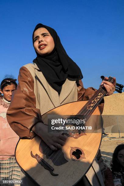 Ruaa Hassouna plays music for Palestinian children on her Oud as Palestinian children participate in an activity aimed to support their mental...