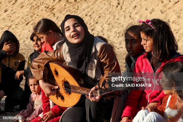 Ruaa Hassouna plays music for Palestinian children on her Oud as Palestinian children participate in an activity aimed to support their mental...