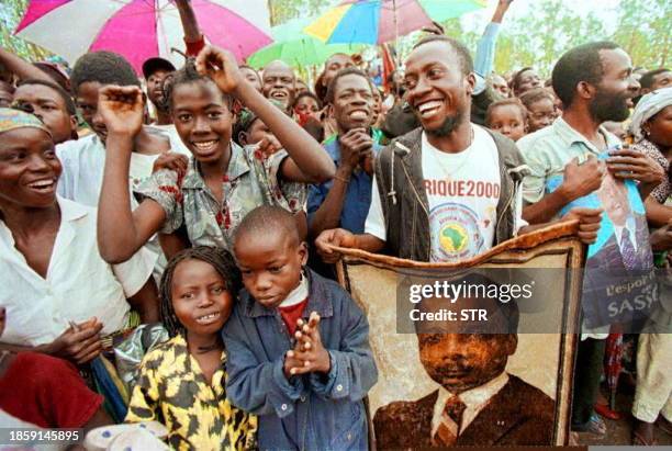 Man holds a poster of Congo's strongman Denis Sassou Nguesso and celebrates with other people Nguesso's arrival in the shattered capital Brazzaville...