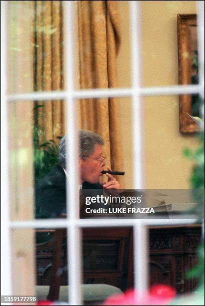 This 27 May 1993 file photo shows US President Bill Clinton as he chews on a cigar in the Oval Office of the White House in Washington, DC as he...