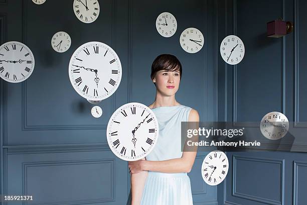 woman standing with hanging clocks - frau uhr stock-fotos und bilder