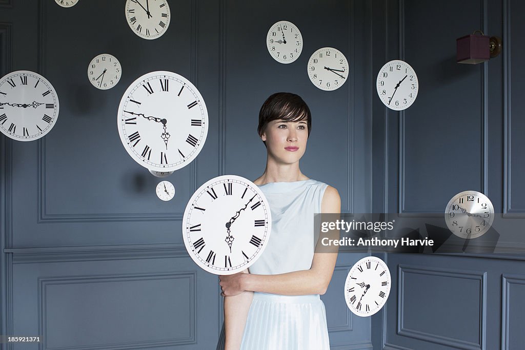 Woman standing with hanging clocks