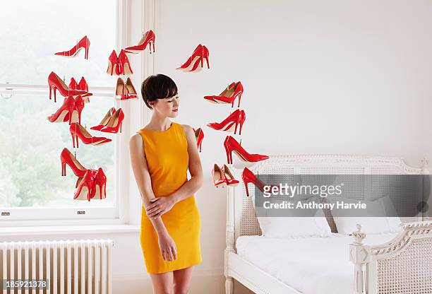woman in bedroom with hanging red shoes - red stiletto shoe stock-fotos und bilder