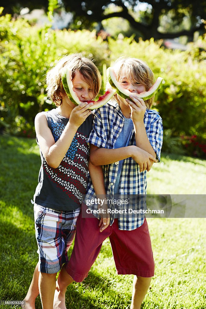 Two boys playing with watermelon rinds.