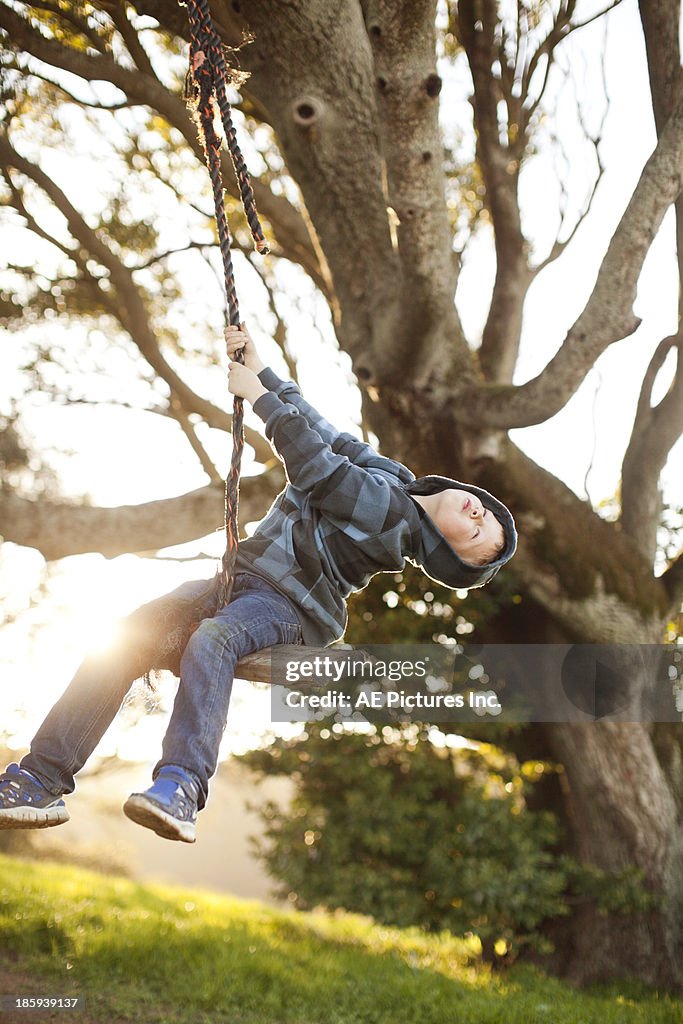 Boy swings carefree from rope swings