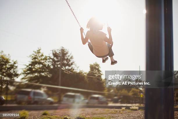 girl swinging in sunset - balançoire photos et images de collection