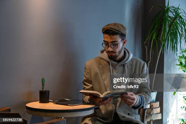 young handsome man in eyewear spending free time in coffee shop. - time life authors stock pictures, royalty-free photos & images