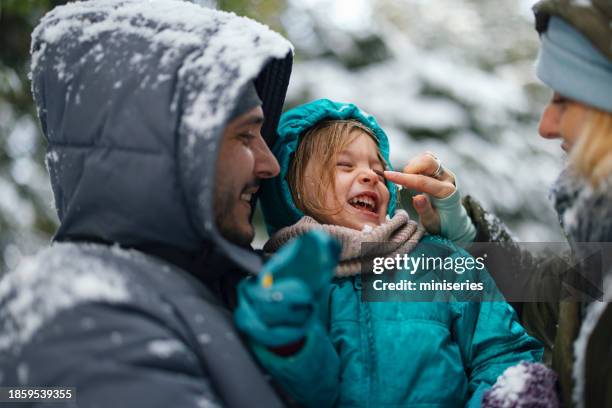 a happy beautiful family enjoying winter holidays - father and mother with their daughter playing in the snow stock pictures, royalty-free photos & images