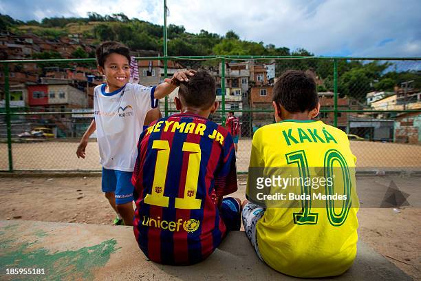 Boys wear jerseys bearing the names of Brazilian team players of Neymar Jr and Kaka while watching a match at the Vila Nova Project in the Morro dos...