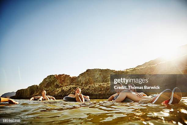 Friends floating on inner tubes in river laughing