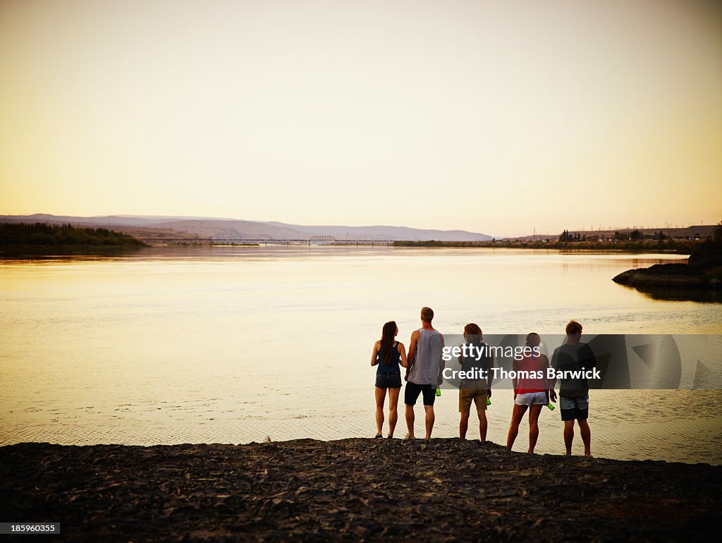 Group of friends looking out over river at sunset