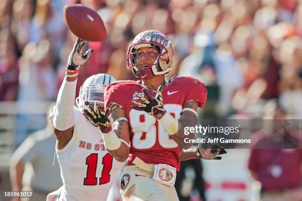 Rashad Greene of the Florida State Seminoles reels in a touchdown pass while Juston Burris of the North Carolina State Wolfpack attempts to defend...