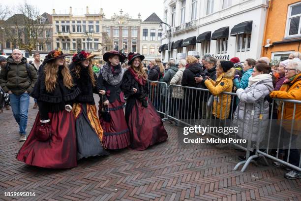 Women wearing Victorian dress welcome the thousands of visitors waiting in line to visit the Dickens Festival on December 16, 2023 in Deventer,...