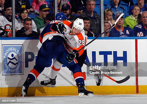 Claude Giroux of the Philadelphia Flyers is checked by Travis Hamonic of the New York Islanders at the Nassau Veterans Memorial Coliseum on October...