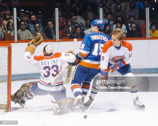 Bryan Trottier of the New York Islanders is sandwiched between goalie Richard Sevigny and Guy LaFleur of the Montreal Canadiens during an attempted...