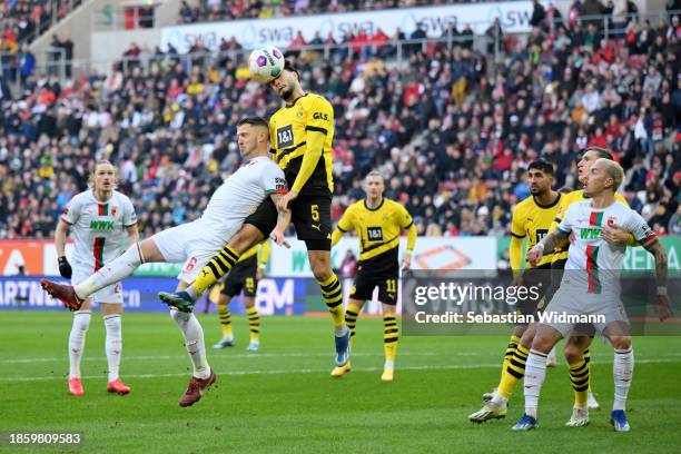 Jeffrey Gouweleeuw of FC Augsburg jumps for the ball with Rami Bensebaini of Borussia Dortmund during the Bundesliga match between FC Augsburg and...