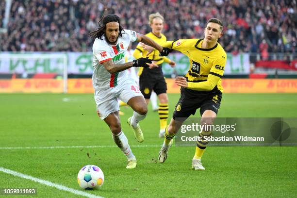 Kevin Mbabu of FC Augsburg battles for possession with Nico Schlotterbeck of Borussia Dortmund during the Bundesliga match between FC Augsburg and...