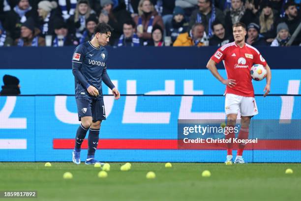 Takuma Asano of VfL Bochum picks up tennis balls after they were thrown on to the pitch by fans in protest against the DFL investors during the...