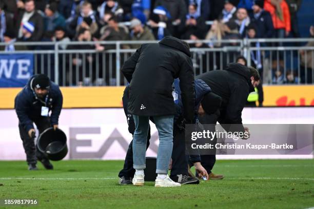 Security collects objects from the pitch thrown by fans of SV Darmstadt 98 during the Bundesliga match between SV Darmstadt 98 and VfL Wolfsburg at...