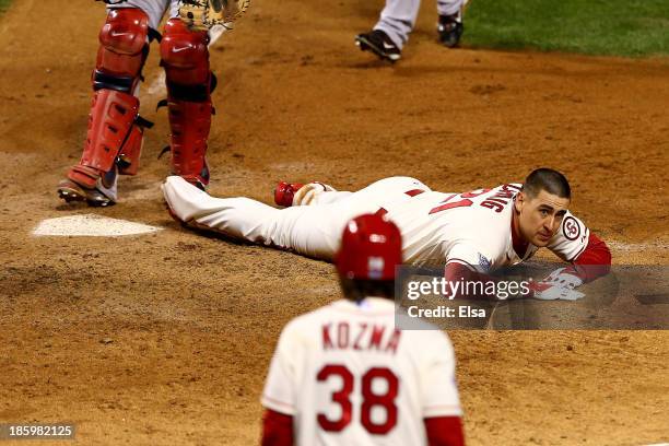 Allen Craig of the St. Louis Cardinals lays next to home plate after scoring the winning run against the Boston Red Sox in the ninth inning during...