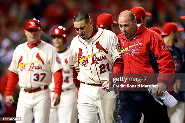 Allen Craig of the St. Louis Cardinals is helped off of the field after scoring the winning run against the Boston Red Sox in the ninth inning of...