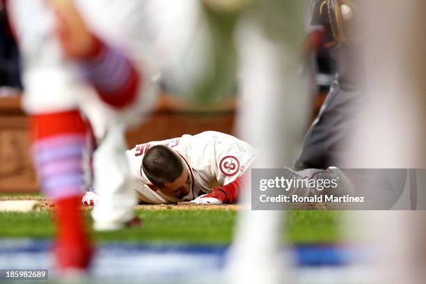 Allen Craig of the St. Louis Cardinals lays next to home plate after scoring the winning run against the Boston Red Sox in the ninth inning during...