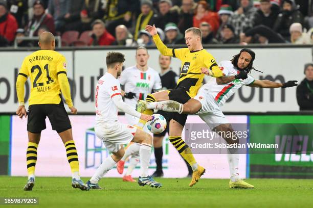 Elvis Rexhbecaj and Kevin Mbabu of FC Augsburg battles for possession with Marco Reus of Borussia Dortmund during the Bundesliga match between FC...