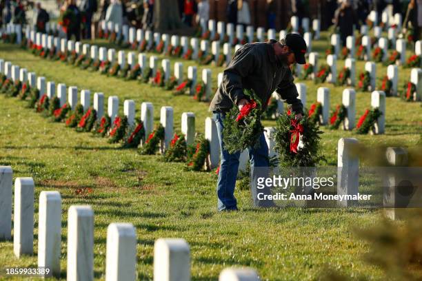 Volunteers place Christmas wreaths on headstones as they participate in Wreaths Across America day at Arlington National Cemetery on December 16,...