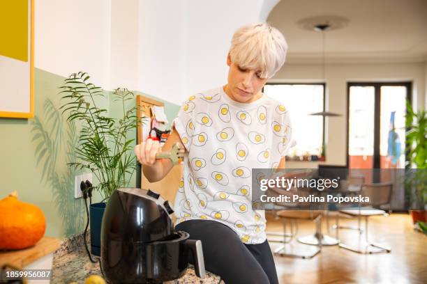 nahaufnahme einer person, die rezepte vom telefon liest - airfryer stock-fotos und bilder