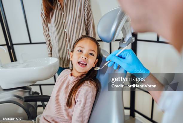 dentist examining a girl's teeth in a dental clinic - pediatric dentistry stock pictures, royalty-free photos & images