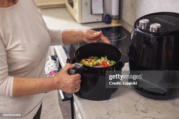 senior woman using air fryer in the kitchen - air fryer stock pictures, royalty-free photos & images