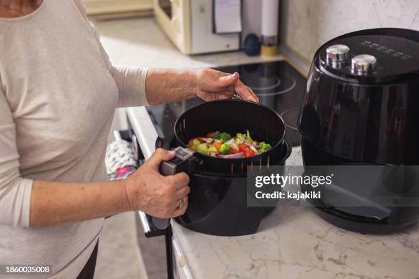 senior woman using air fryer in the kitchen - airfryer stock pictures, royalty-free photos & images